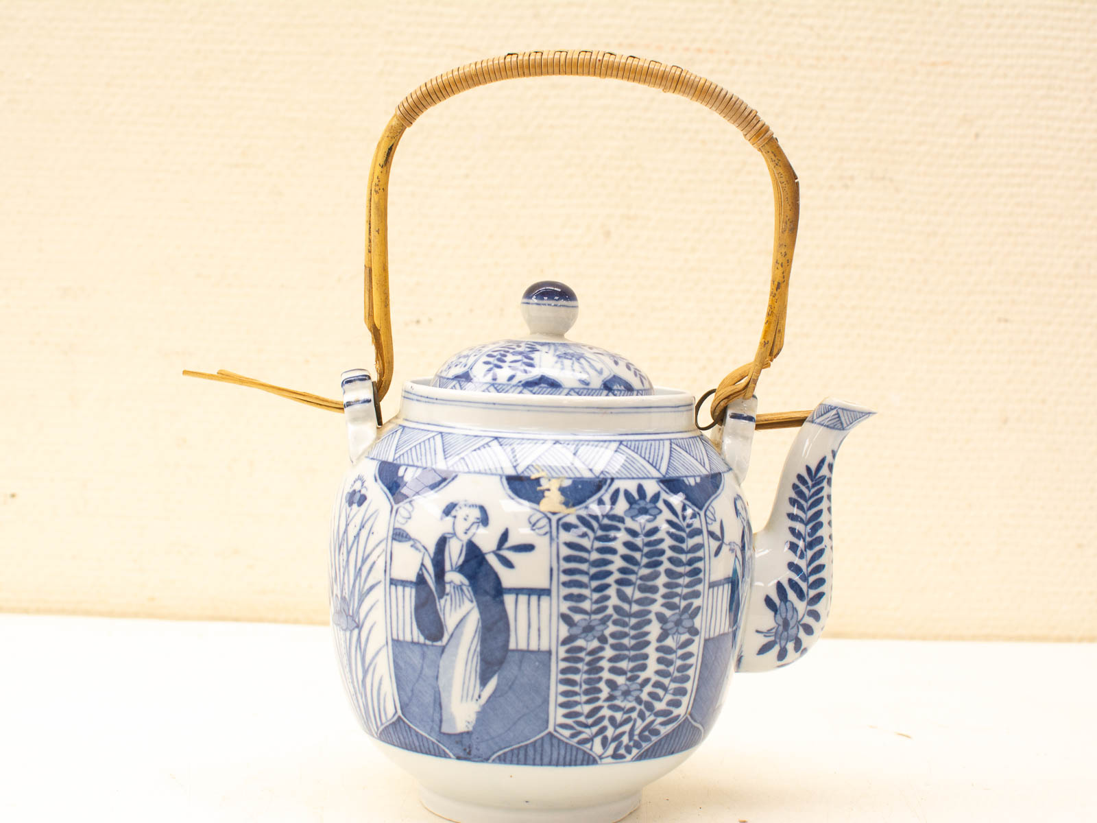 Elegant blue and white teapot with bamboo handle, showcasing exquisite ceramic craftsmanship and floral designs.