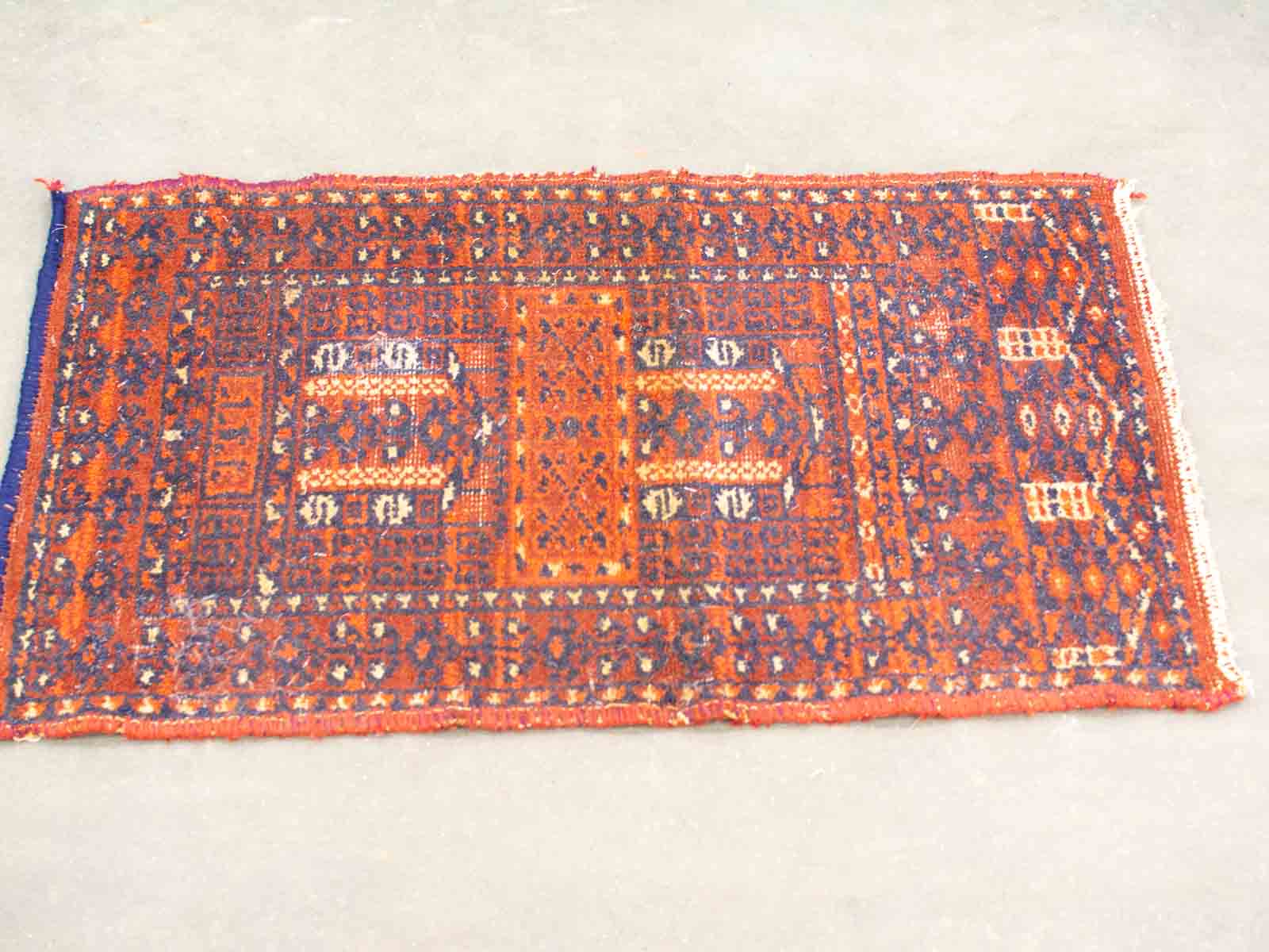 Traditional handwoven rug in deep red and blue with intricate geometric and floral patterns.