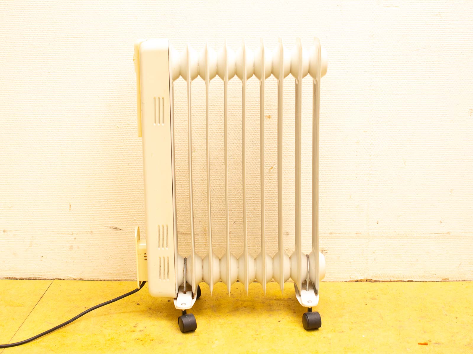 Vintage cream oil-filled radiator with wheels for easy indoor heating and stylish decor.