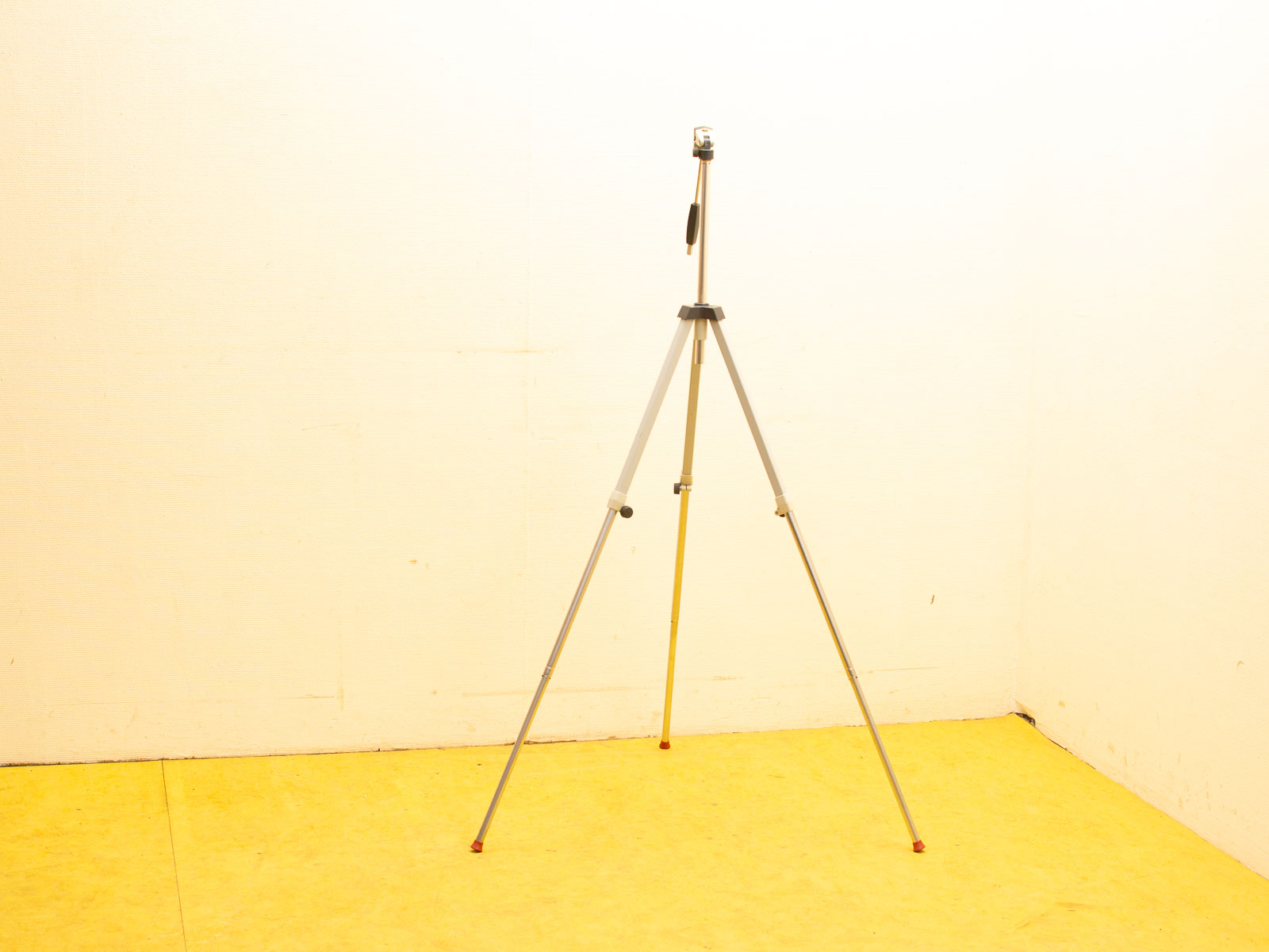 Stylish tripod on yellow floor in minimalistic space, perfect for photographers and videographers.