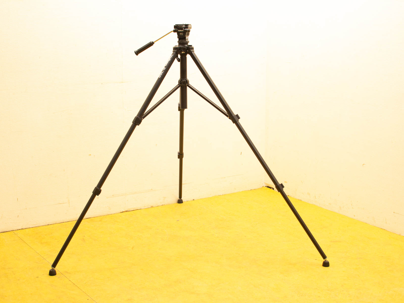 Professional black tripod with adjustable legs and gold background for stable photography.