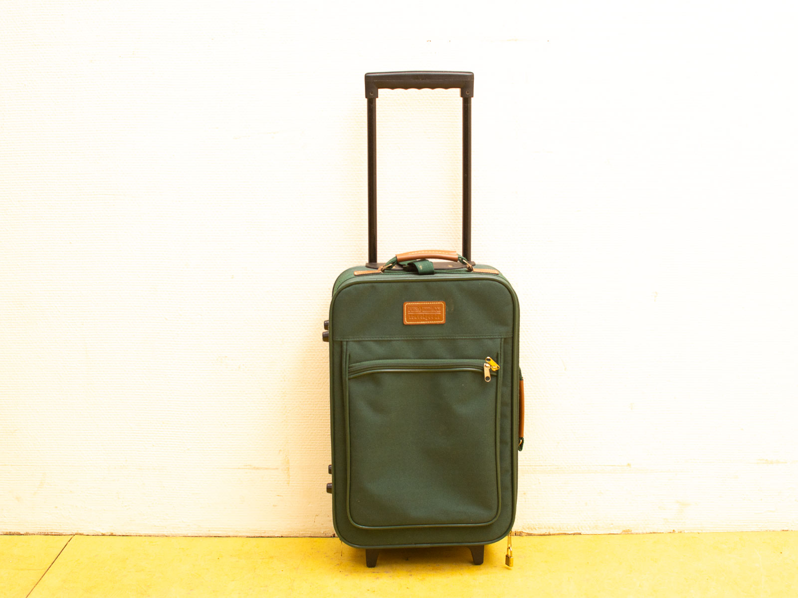 Stylish deep green suitcase with wheels, telescoping handle, and convenient zipped pocket for travel.