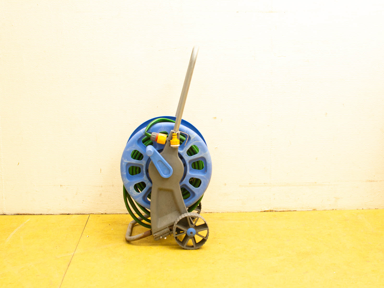 Blue garden hose reel with green hose, ergonomic handle, and mobile gray base for easy use.