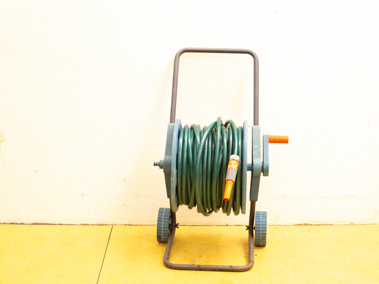 Green garden hose reel on wheels, designed for easy mobility and efficient gardening.