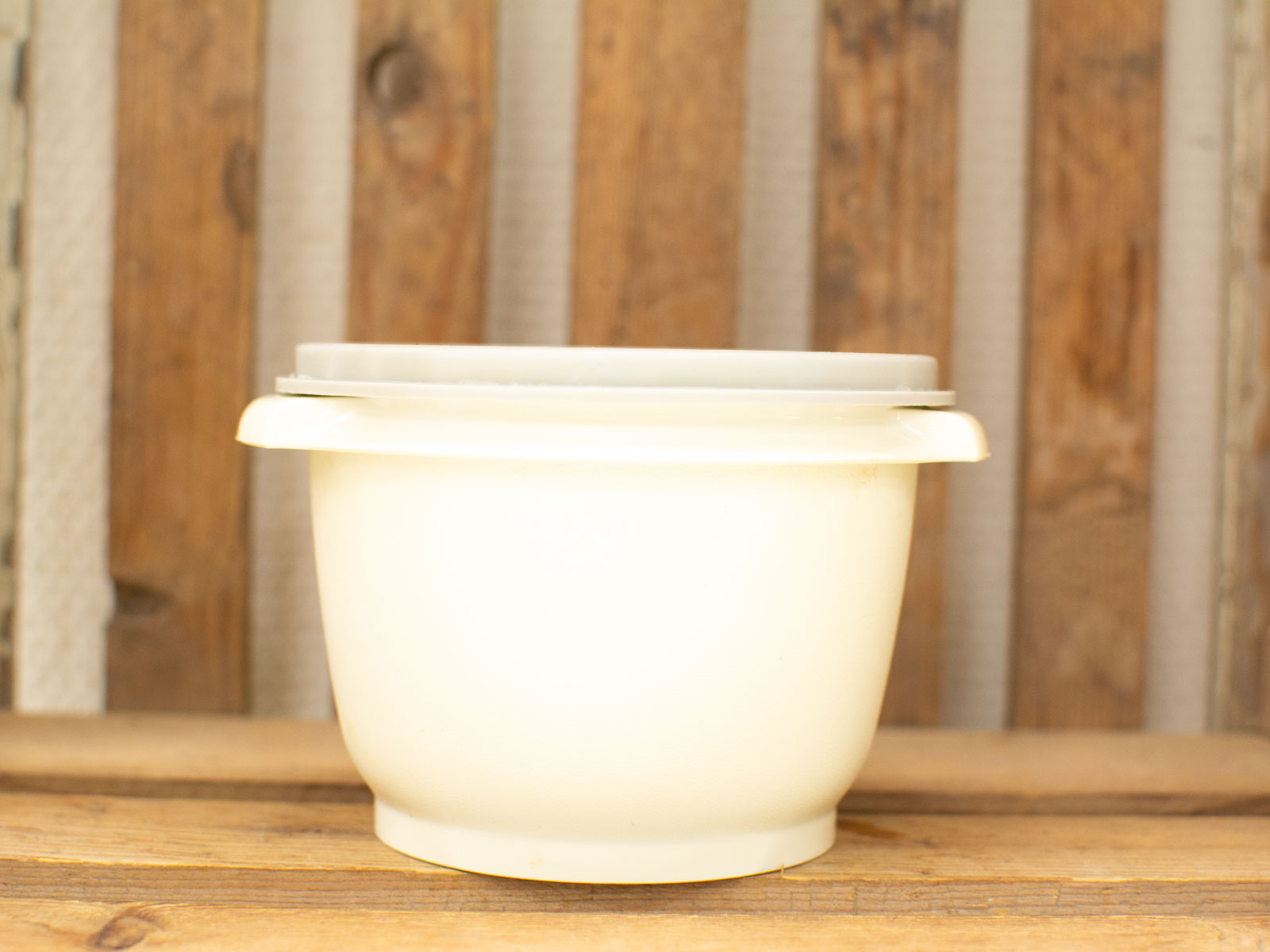 Elegant cream bowl with lid on rustic wood, perfect for cozy kitchens and serving meals.