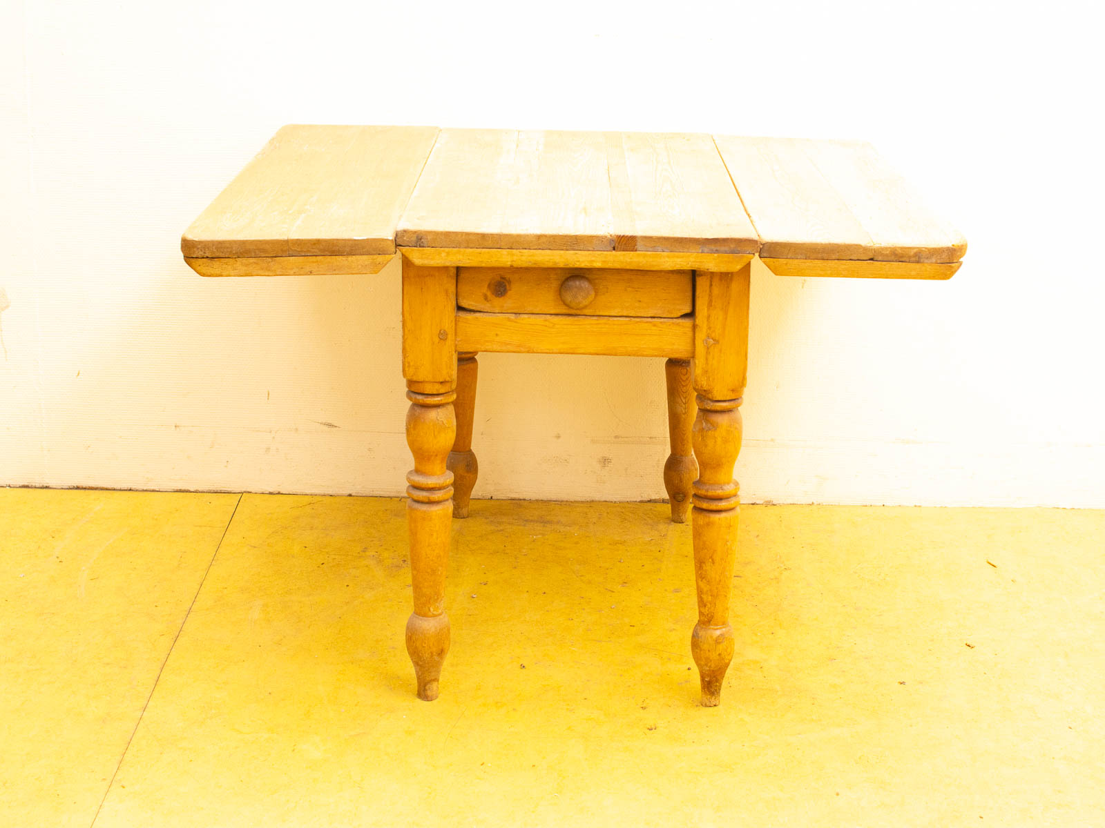 Rustic wooden drop-leaf table with a round drawer, perfect for cozy spaces and home decor.