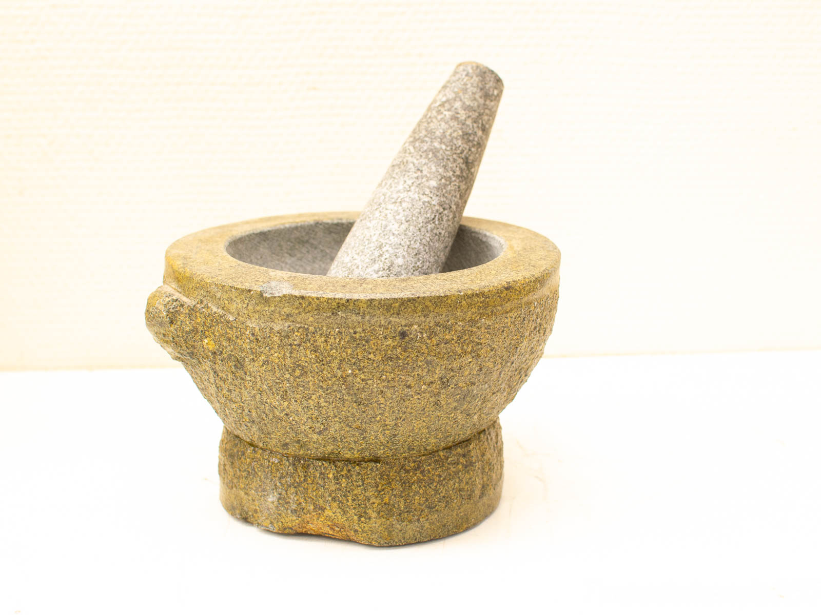 Traditional stone mortar and pestle, essential for grinding spices and herbs in cooking.