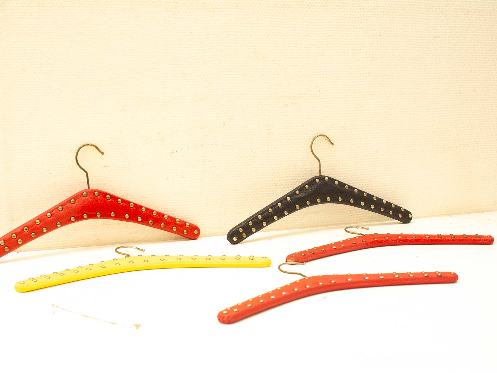 Vibrant vintage clothing hangers in red, yellow, and black with stylish metallic studs.