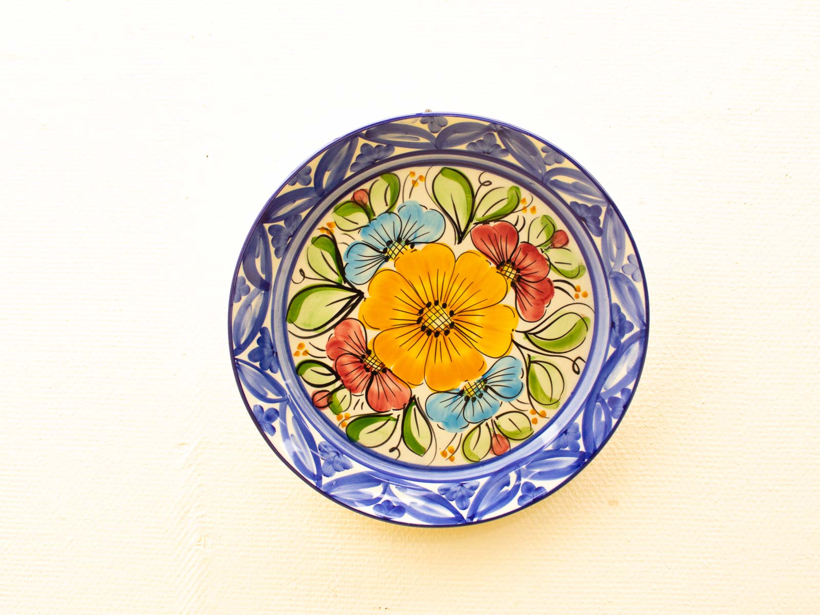 Vibrant vintage ceramic plate with yellow flowers, red and blue blooms, and intricate blue border.