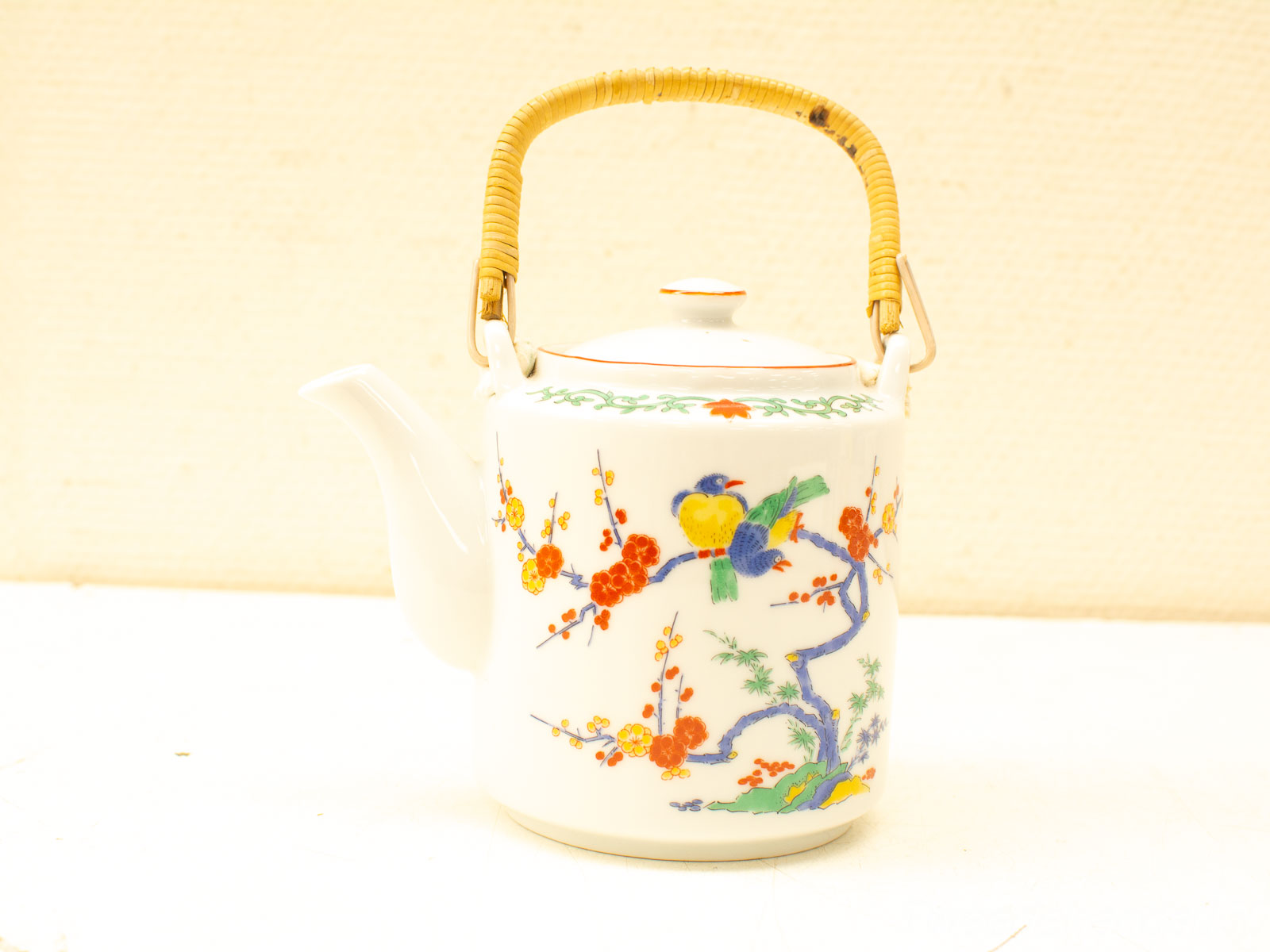 Charming vintage ceramic teapot with floral design and bamboo handle, perfect for tea lovers.