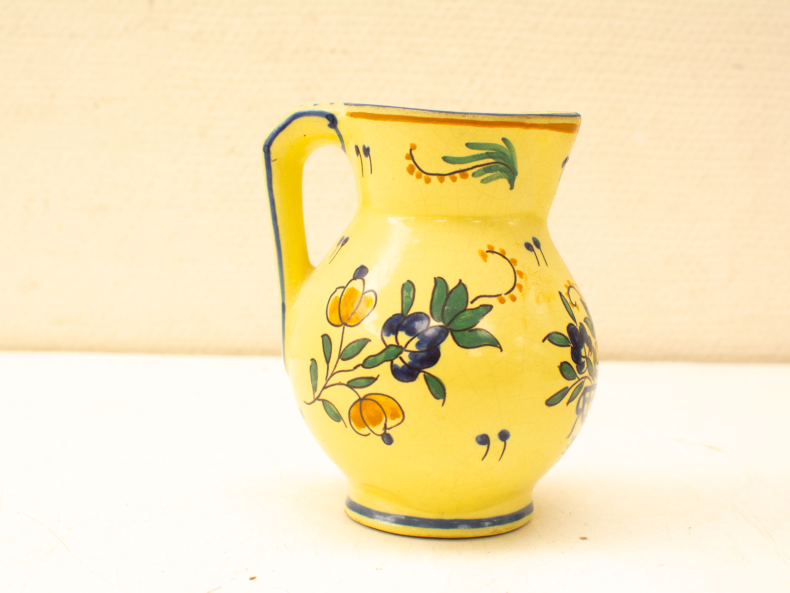 Charming yellow ceramic pitcher with floral designs, perfect for home decor and collectors.