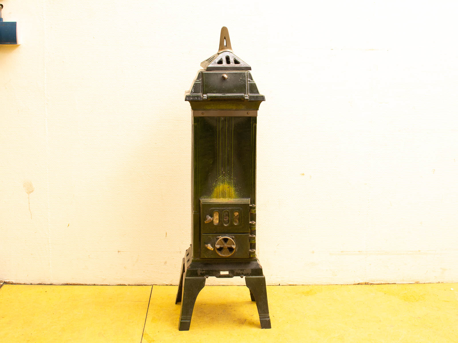 Vintage green metal heater with decorative cap, showcasing intricate design and nostalgic charm.