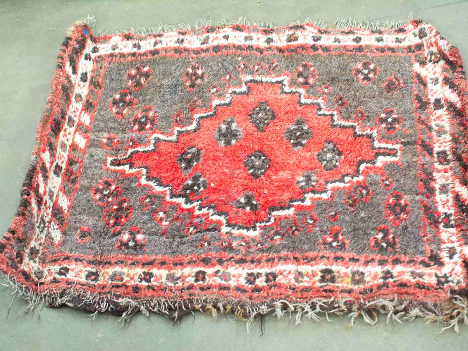 Vintage handwoven rug with geometric patterns in red and black, adding warmth and character.