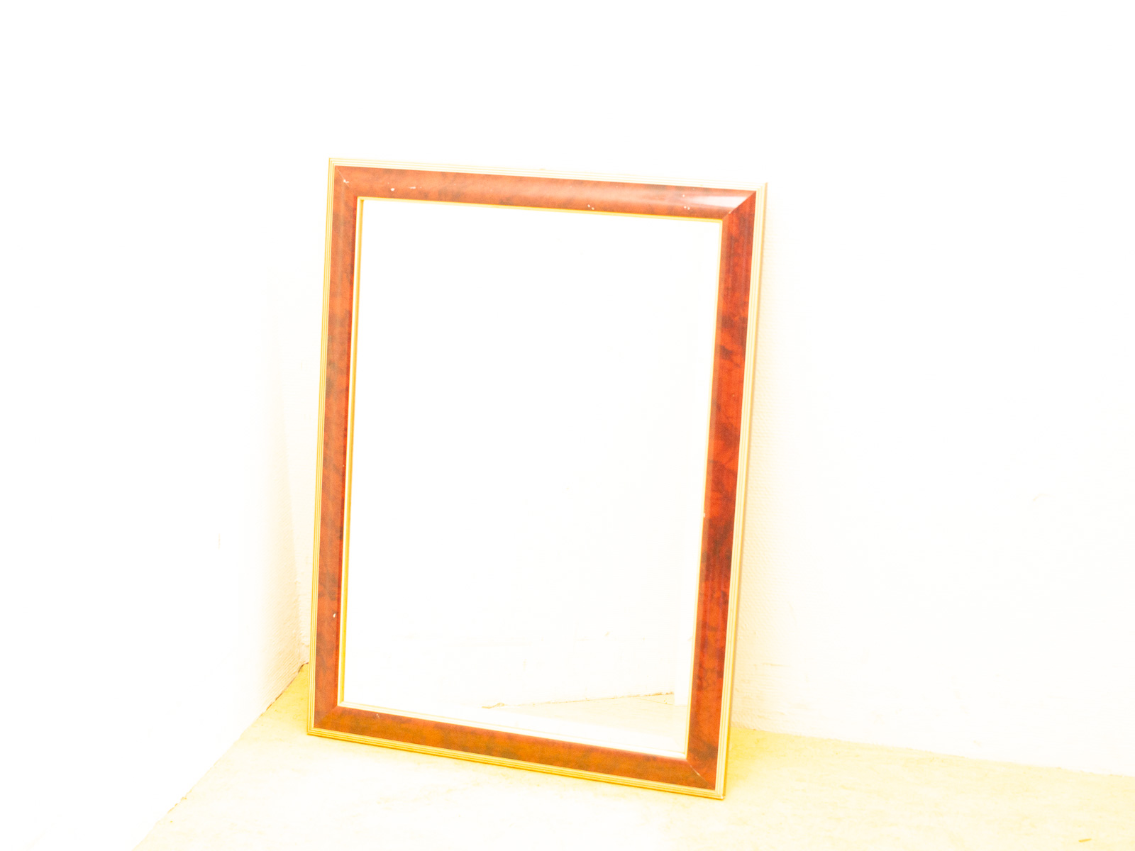 Elegant vintage wooden frame with mirror in corner, perfect for showcasing memories or art.