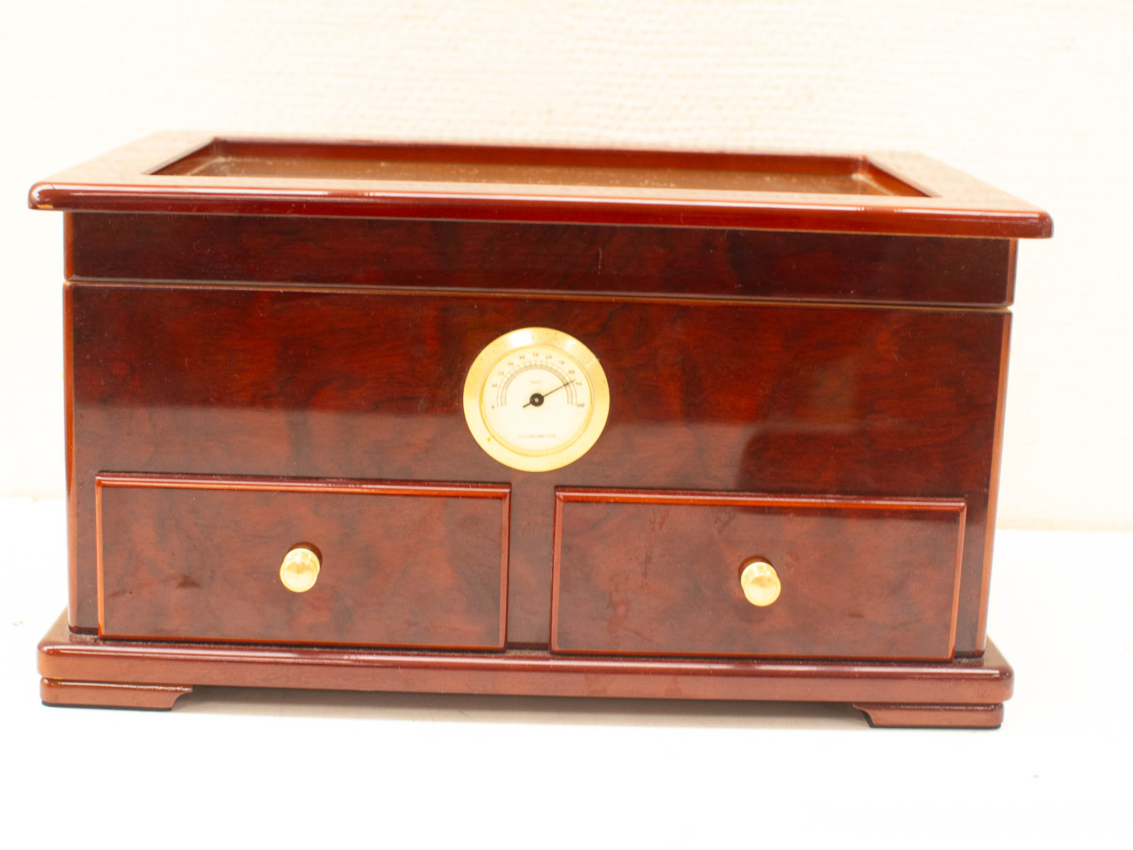 Elegant mahogany box with gold gauge and drawers, perfect for stylish storage solutions.