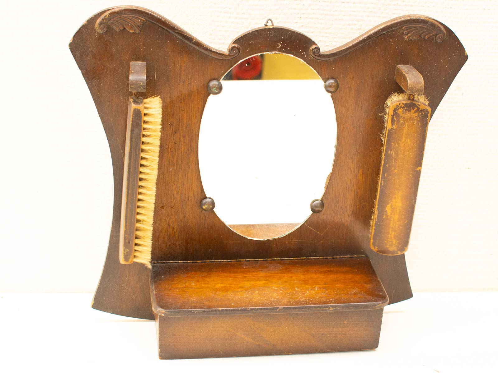 Charming vintage wooden vanity mirror with ornate frame and functional brush and comb holders.