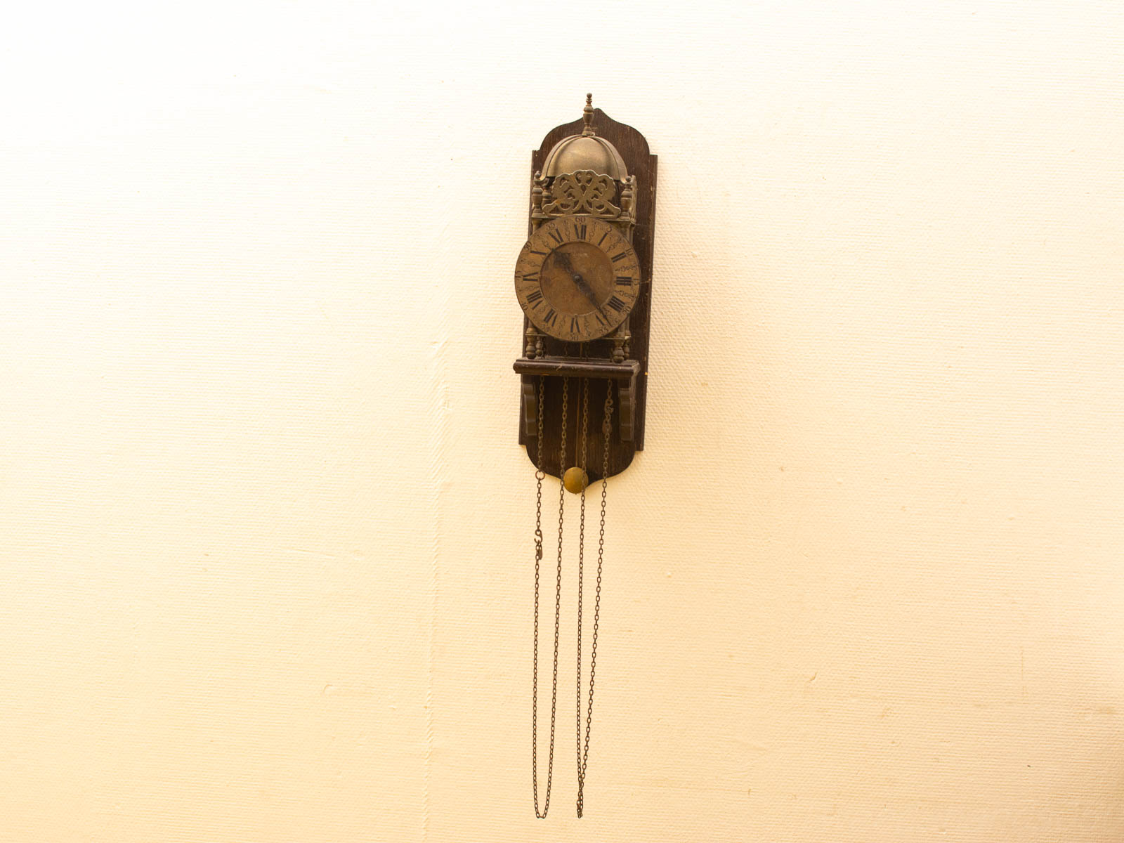 Elegant antique wall clock with pendulum, wooden finish, and Roman numerals for timeless decor.