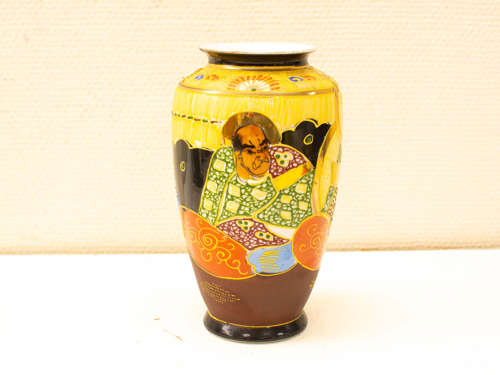 Vibrant vintage vase featuring traditional figures and intricate patterns in yellow and black.