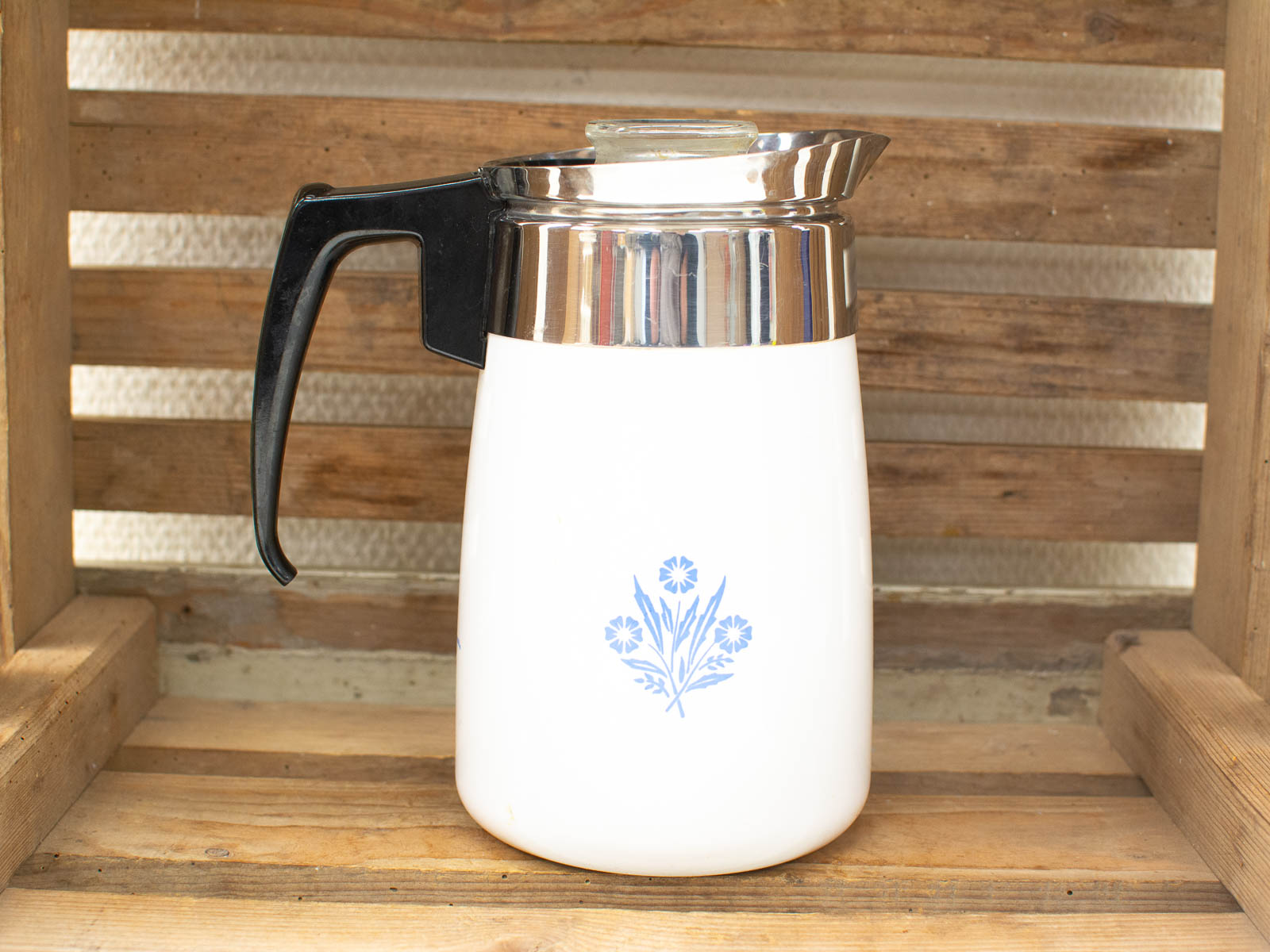 Vintage coffee pot with blue floral design, elegant white body, and shiny metallic lid.