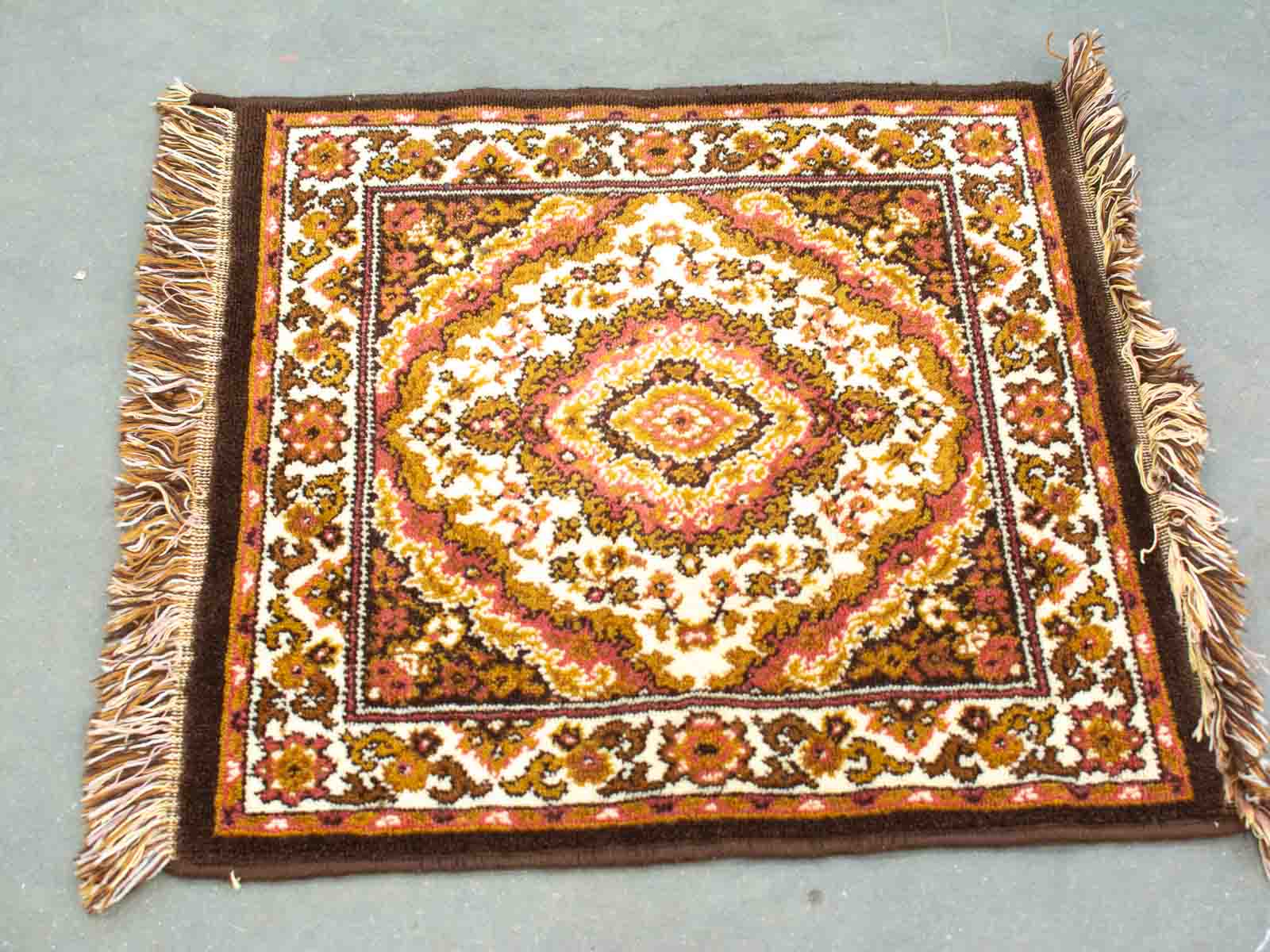 Elegant vintage rug with intricate patterns in warm hues, featuring charming fringed edges.