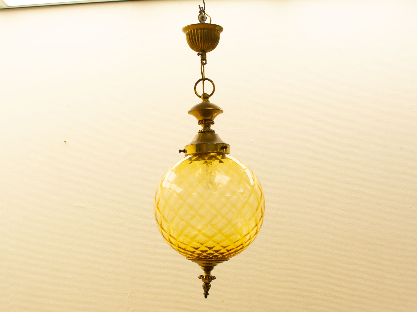 Elegant amber glass pendant light with vintage brass fixture, perfect for any stylish space.