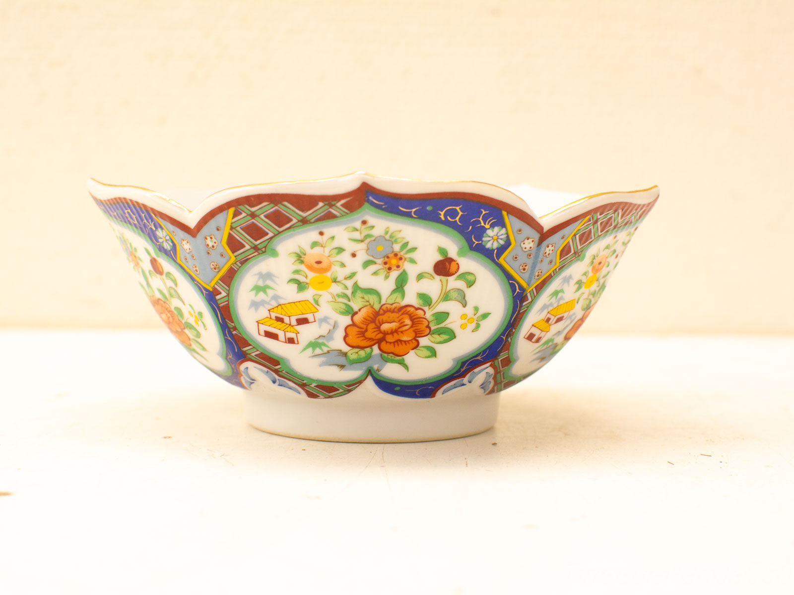 Vibrant hand-painted porcelain bowl with scalloped edges and floral designs, perfect for decor or serving.