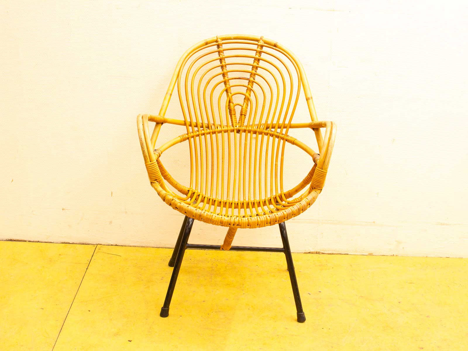 Stylish rattan chair with modern design on vibrant yellow floor, ideal for any interior.