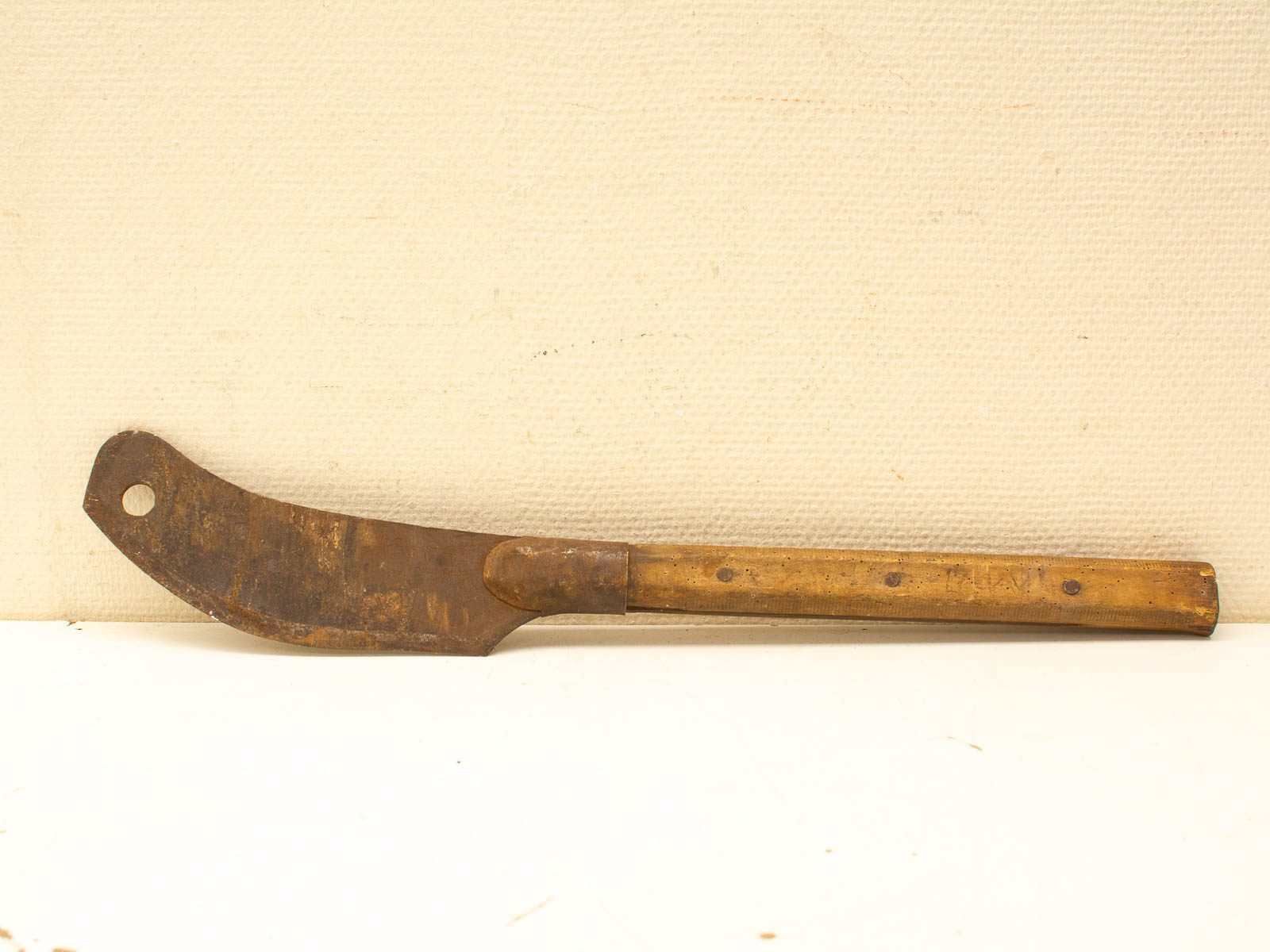 Vintage curved gardening tool with wooden handle, showcasing wear and craftsmanship for garden enthusiasts.