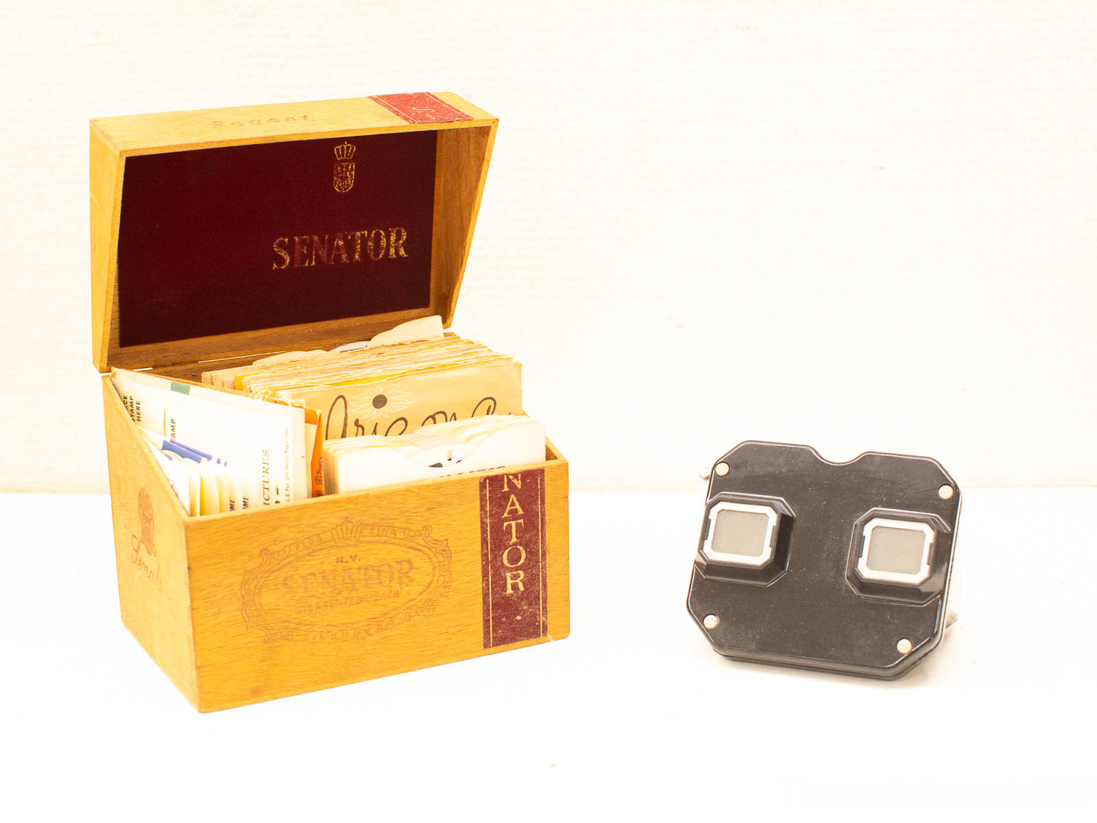 Vintage Senator box with photographs and modern camera accessory, blending nostalgia and contemporary design.