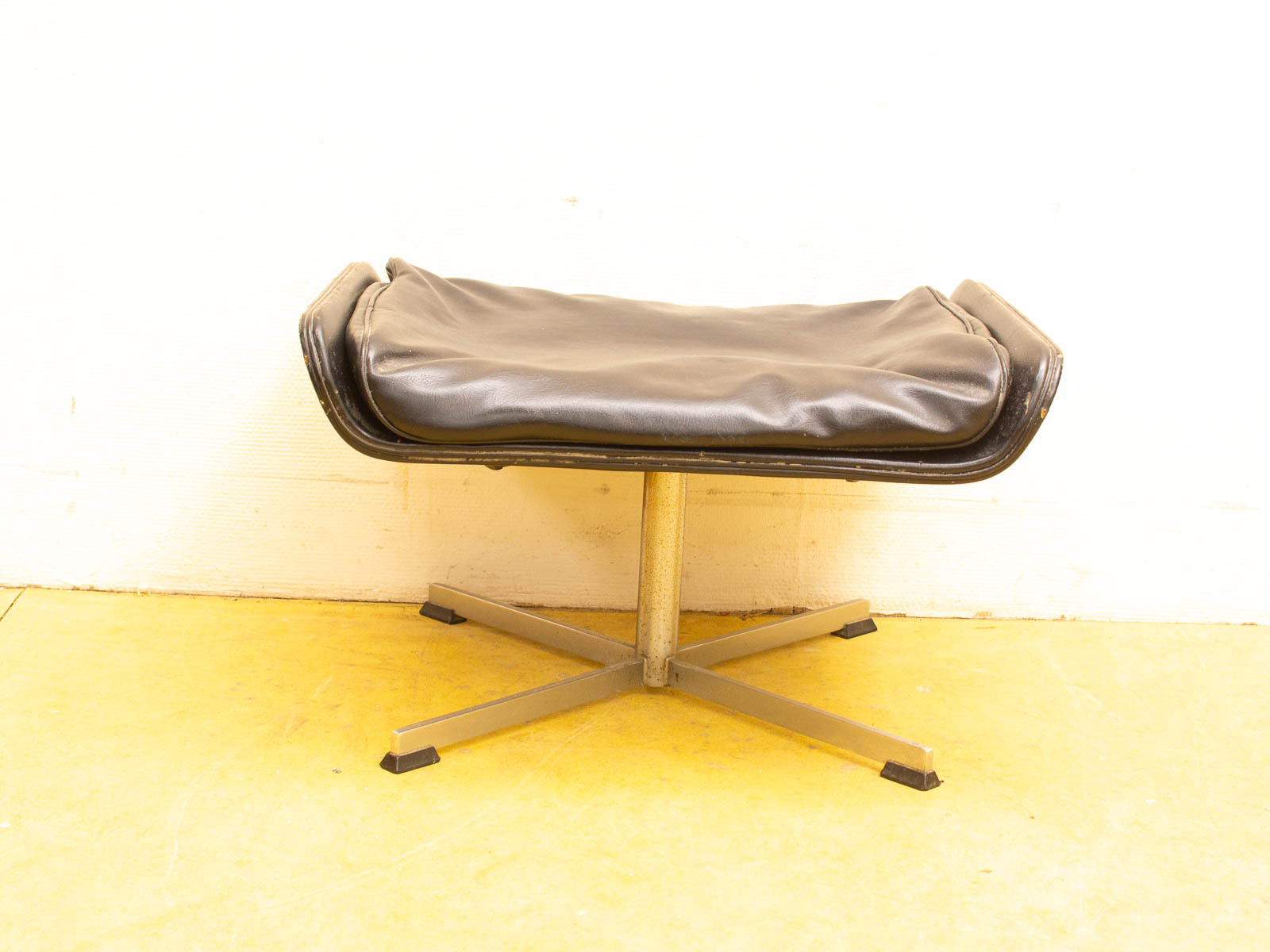 Sleek black minimalist stool with synthetic leather seat and sturdy metal base for any setting.