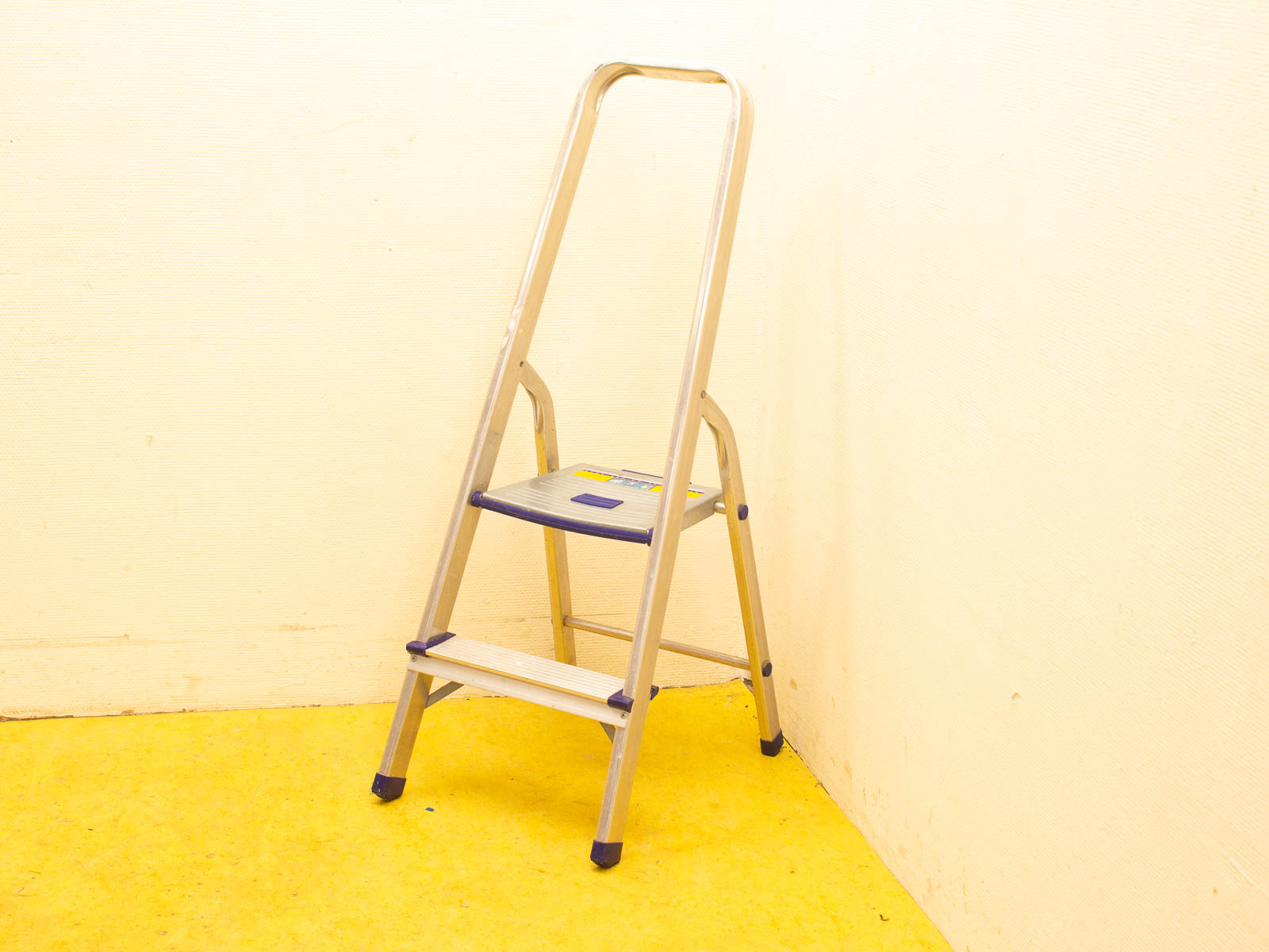 Sleek vintage folding ladder against a pale yellow wall, perfect for home improvement tasks.