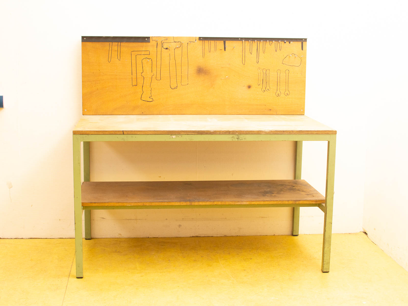 Charming vintage workbench with a green metal frame, wood top, and tool organizer panel.