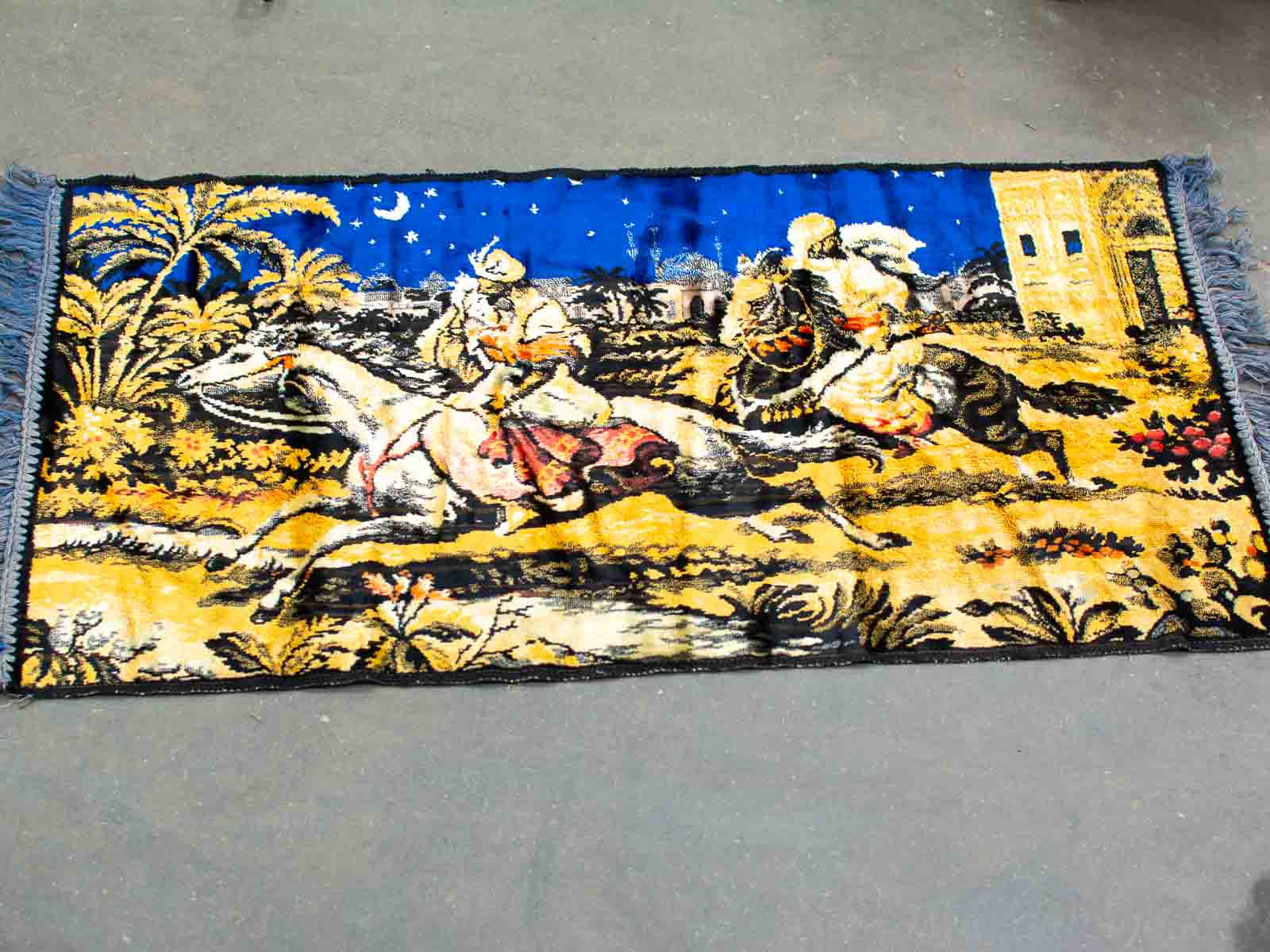 Vibrant woven rug depicting two horsemen chasing under a starry night sky.