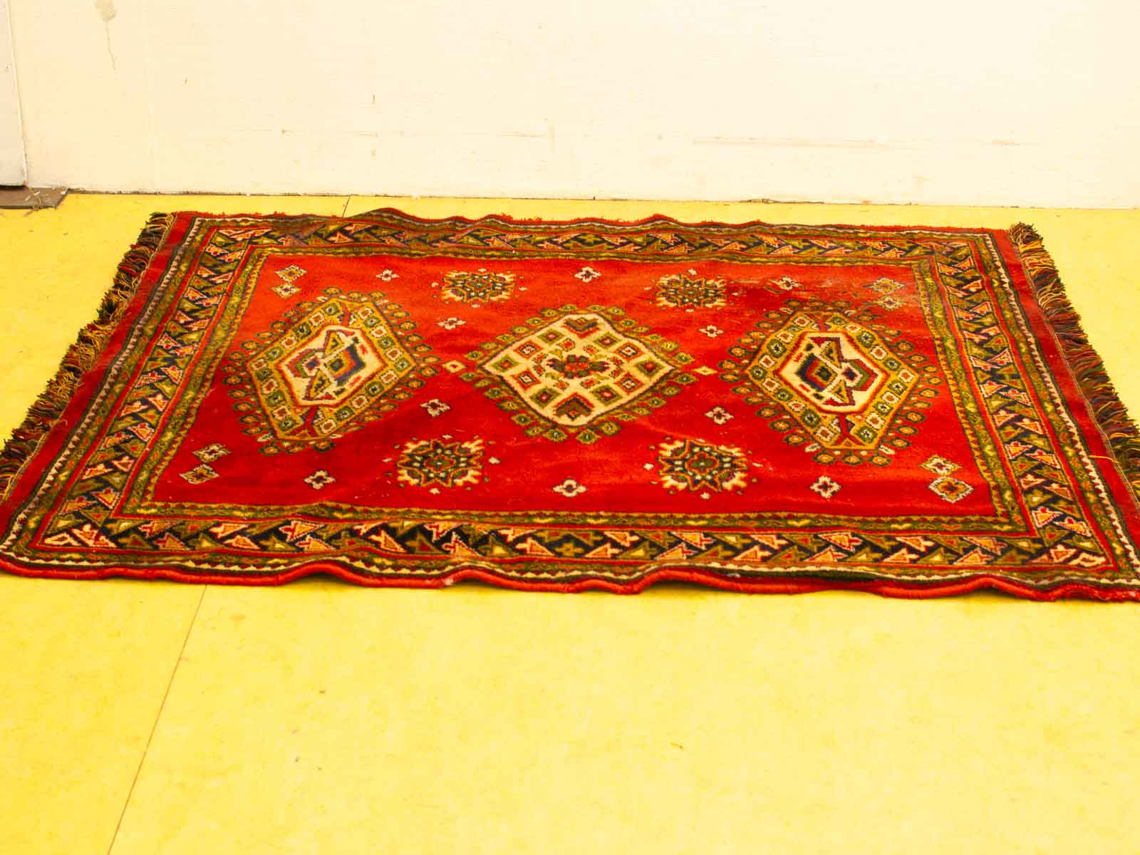 Vibrant red vintage rug with intricate geometric patterns, enhancing any rooms charm and warmth.