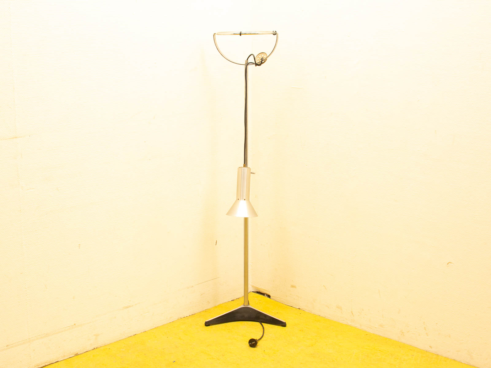 Sleek modern floor lamp with conical shade, enhancing a stylish yellow interior.