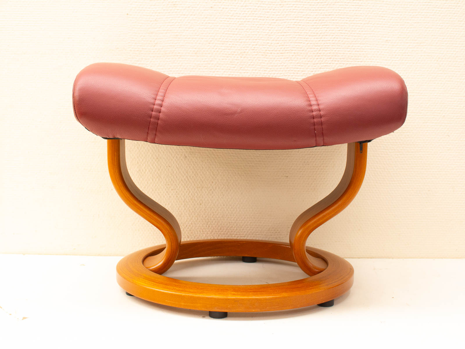 Elegant burgundy leather stool with modern design and sturdy wooden frame for stylish comfort.