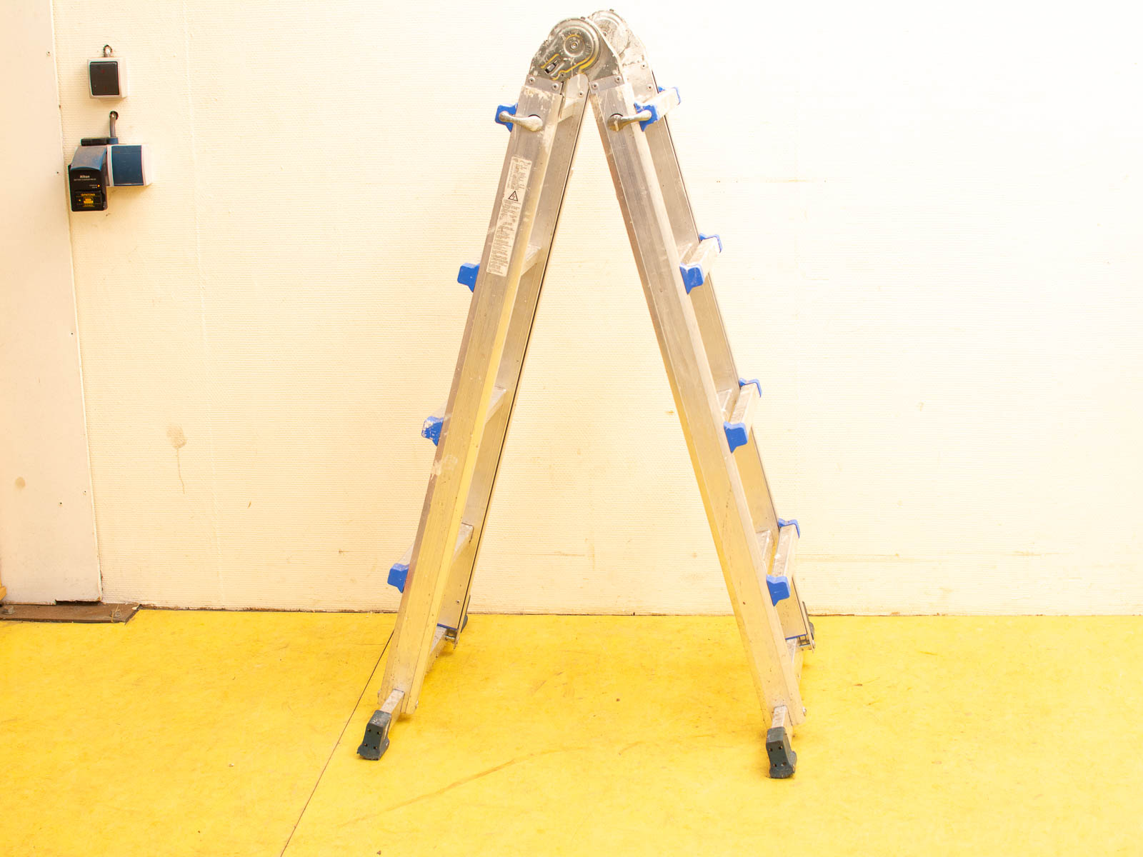 Aluminum step ladder against a white wall in a bright, functional workspace.