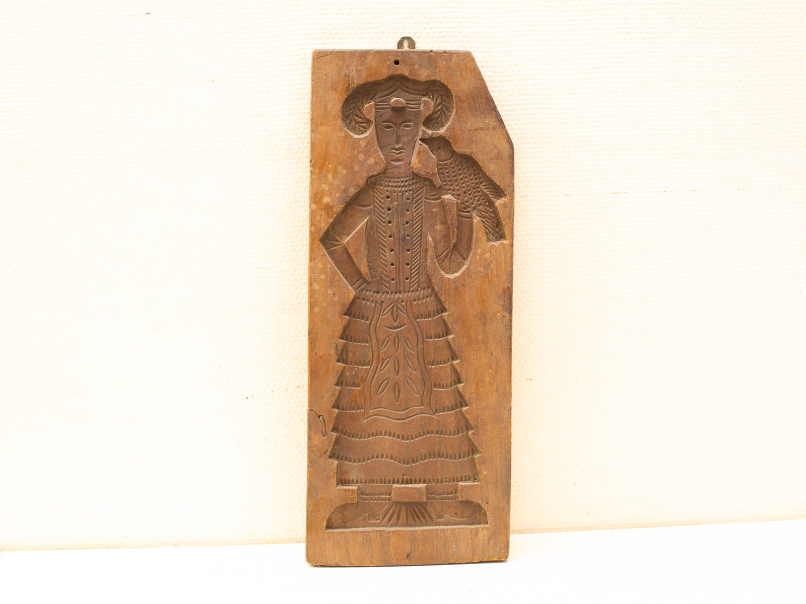 Intricate wooden carving of a woman with a bird, showcasing cultural artistry and craftsmanship.