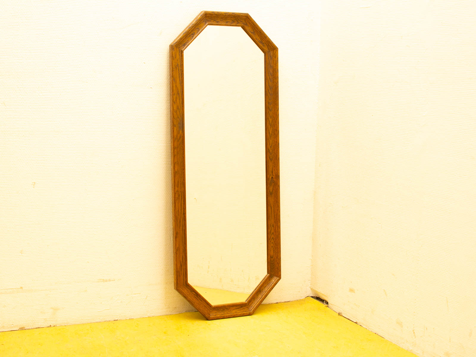 Elegant octagonal wooden mirror in the corner, enhancing light and warmth with vibrant yellow flooring.