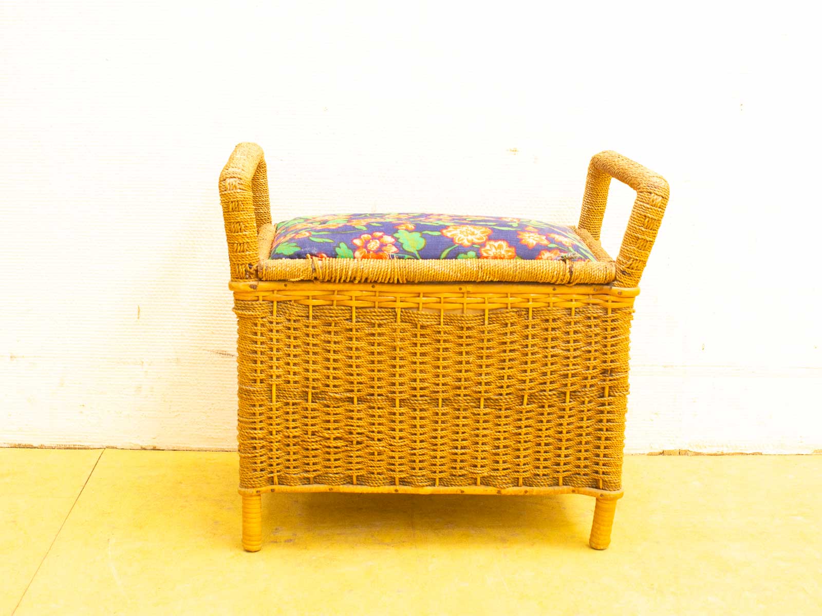 Charming wicker storage bench with floral cushion, perfect for seating and stylish organization.