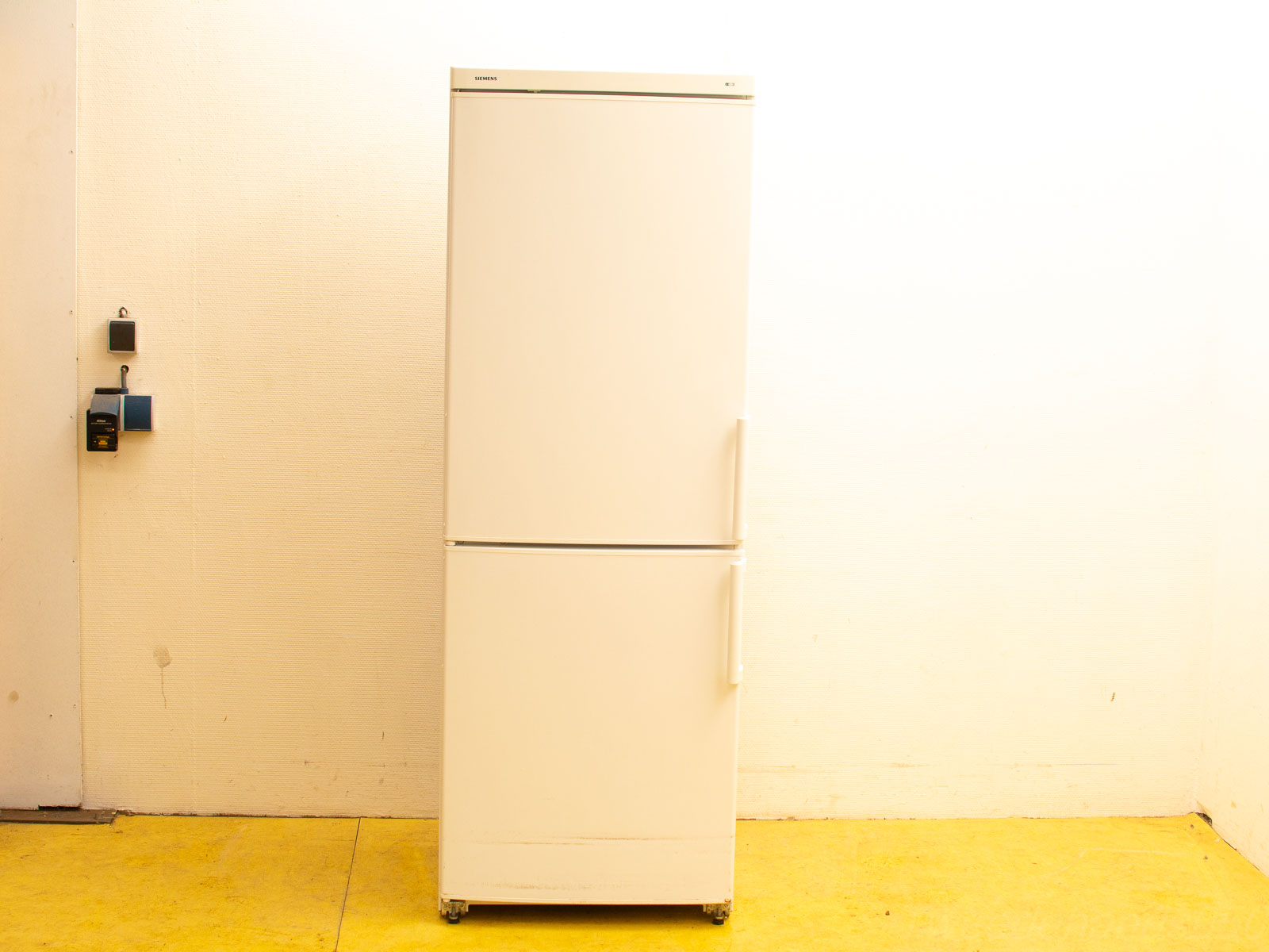 Sleek minimalist white refrigerator with organized compartments and vibrant yellow floor for a stylish kitchen.