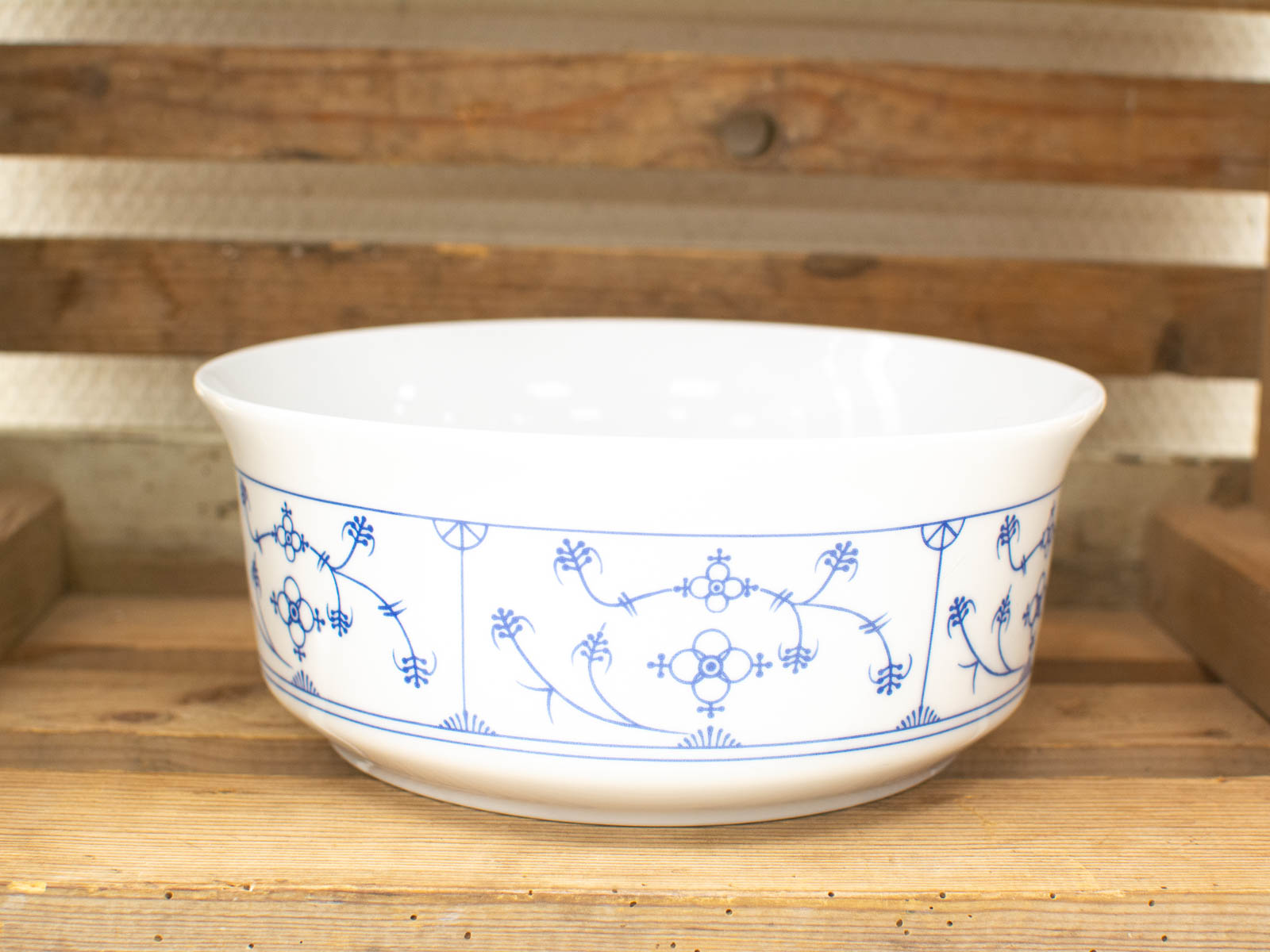 Elegant white porcelain bowl with blue patterns on rustic wooden surface. Perfect for dining or decor.