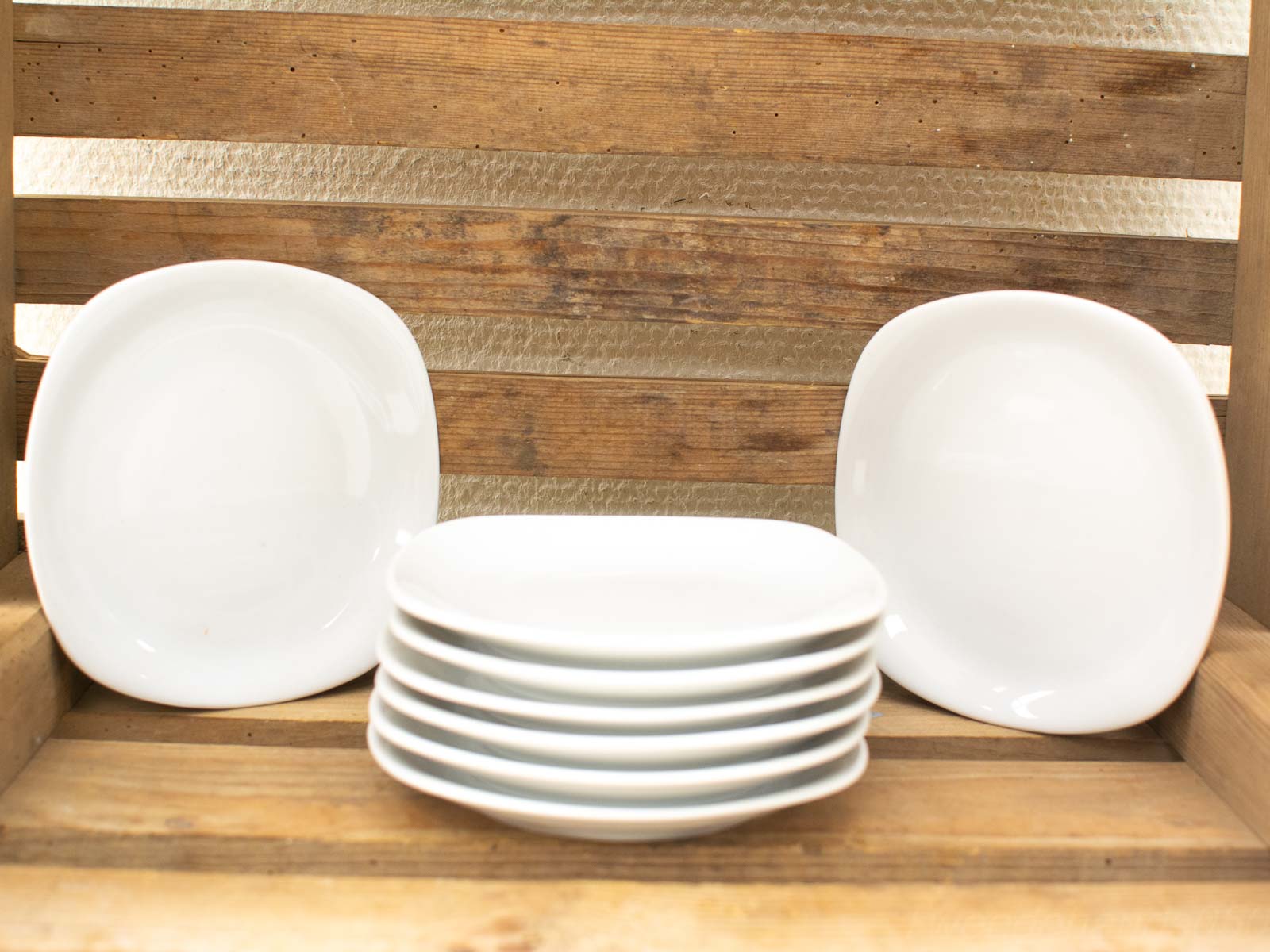 Elegant white square plates on rustic wood, perfect for a charming dining experience.