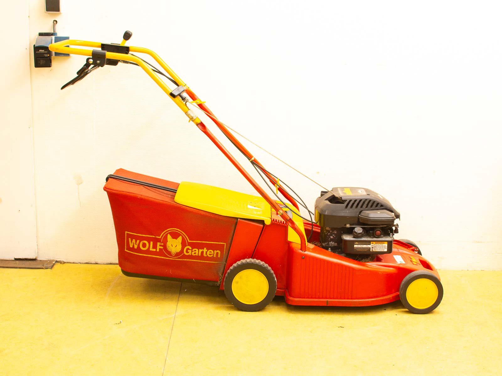 Compact vintage WOLF Garten red and yellow lawn mower, ideal for small lawns and gardens.