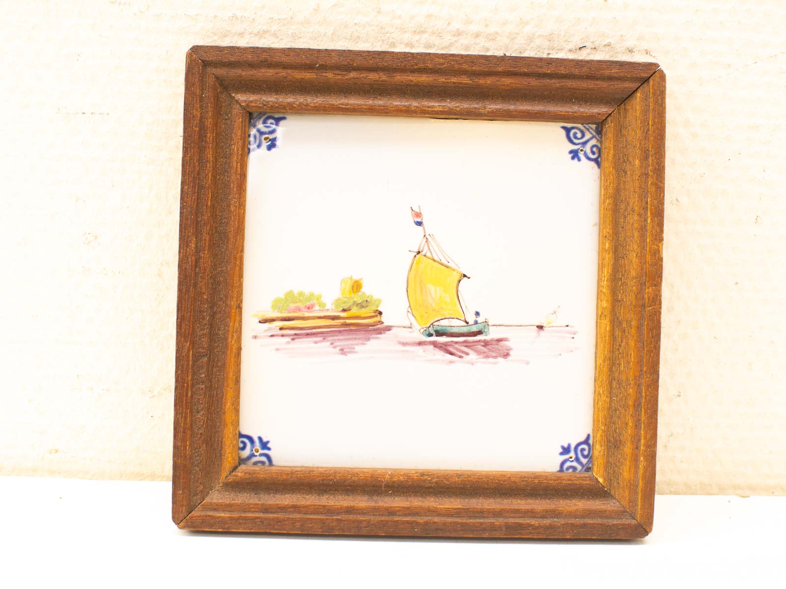 Tranquil ceramic tile art featuring a yellow sailboat in a rustic wooden frame.