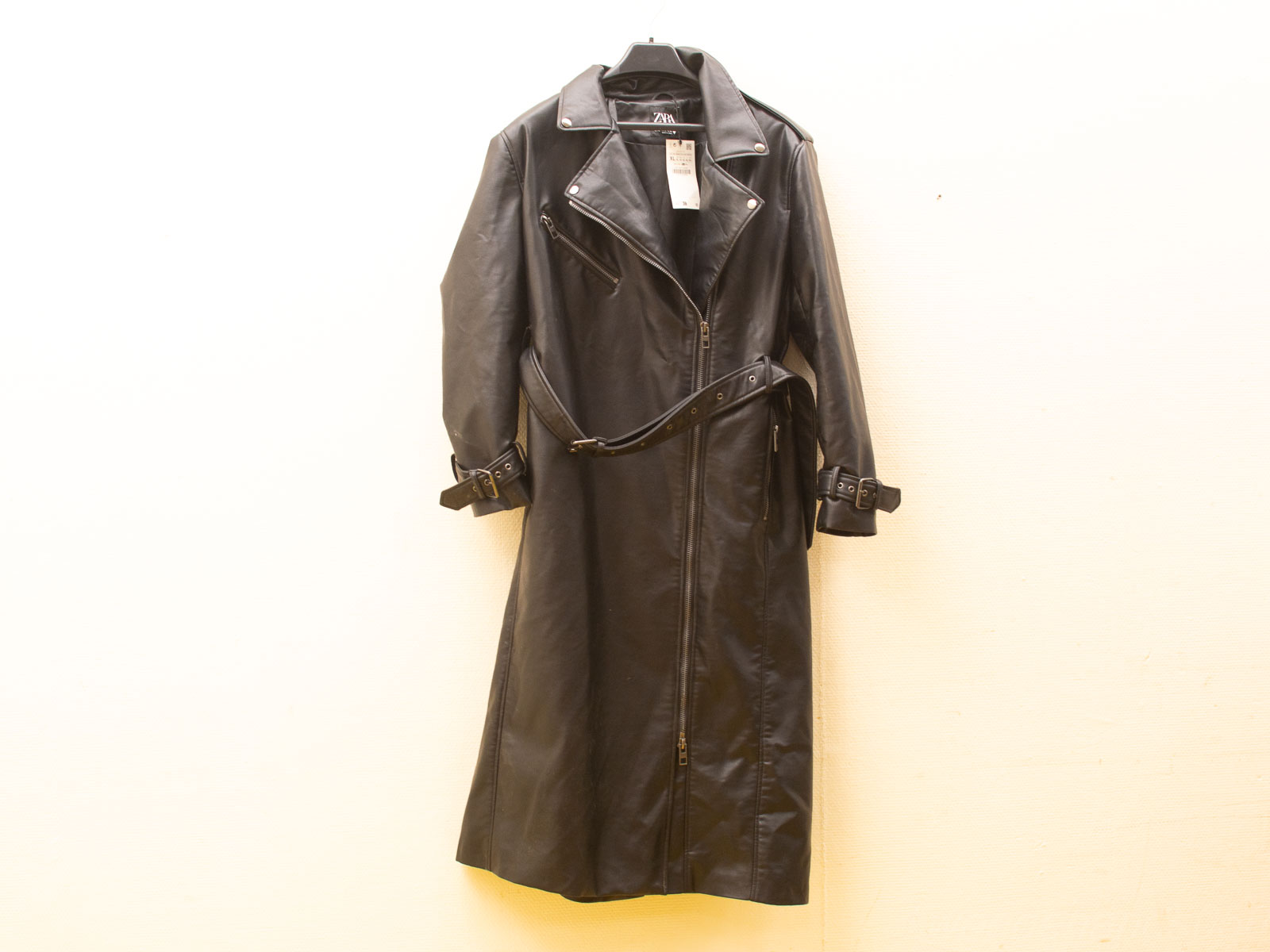 Stylish black leather long coat with belt, notched collar, and adjustable cuffs for versatile elegance.