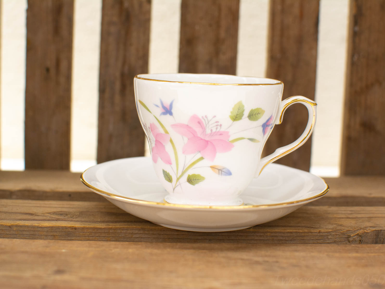 Elegant floral porcelain teacup and saucer on rustic wooden table, perfect for tea moments.