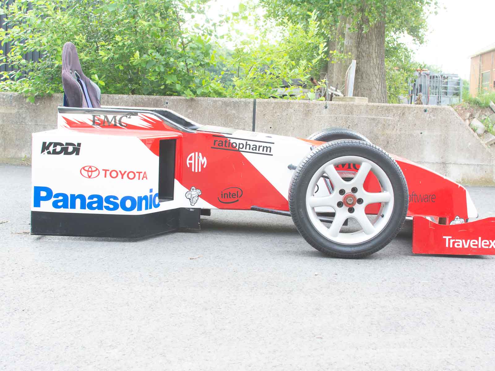 Zijkant van de replica F1-auto met prominente sponsorlogo's en race-ready design.