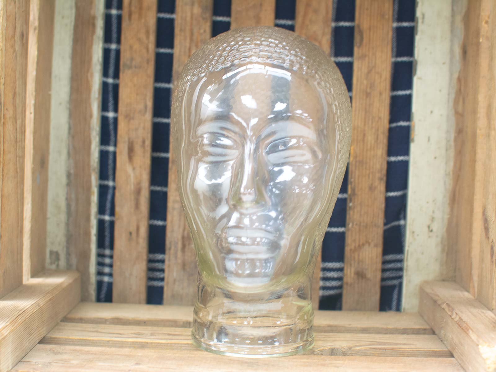 Stunning glass head sculpture with detailed features, set against a rustic wooden backdrop.