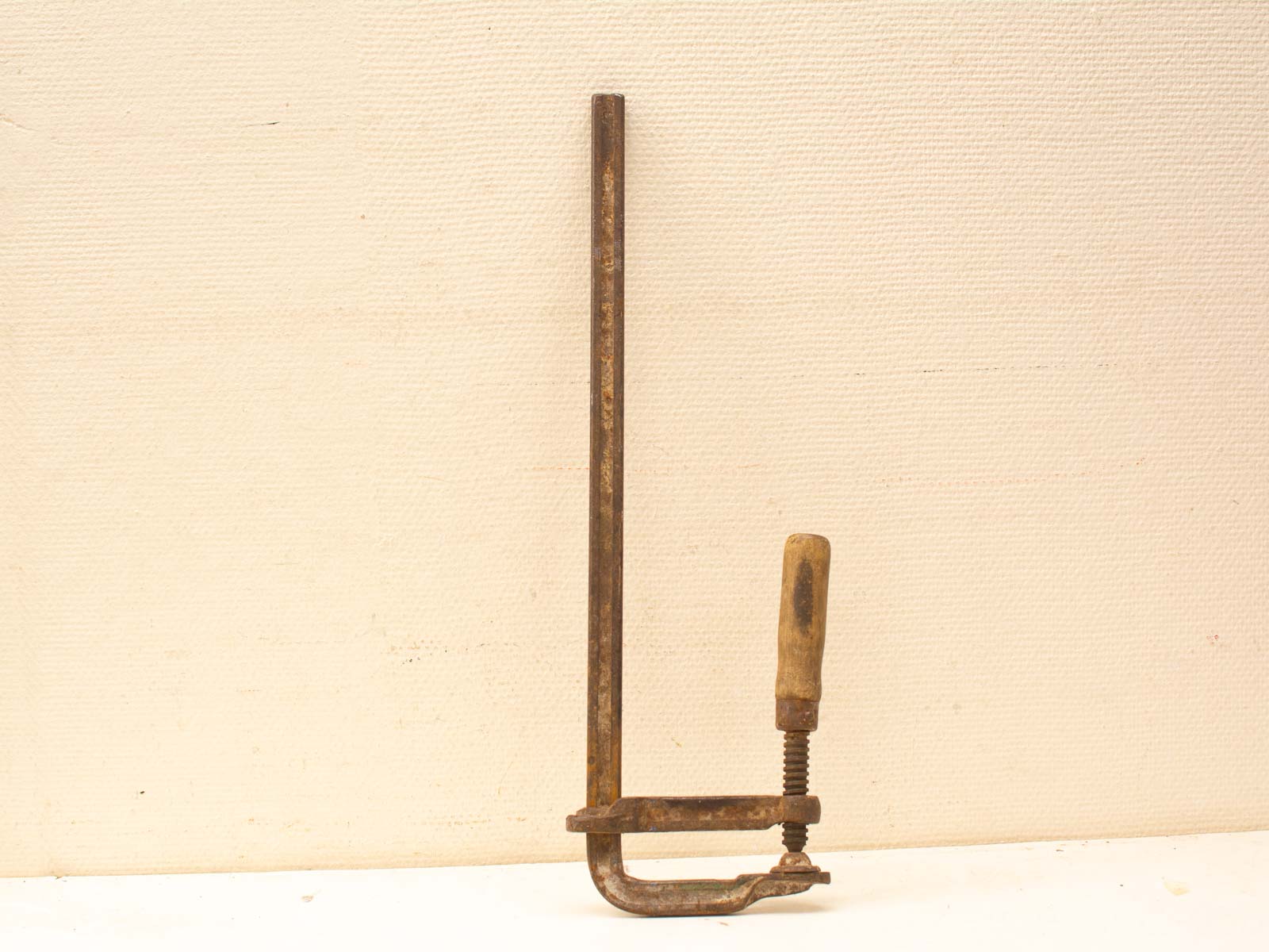 Vintage C-clamp with wooden handle, a well-used tool for woodworking and metalworking tasks.